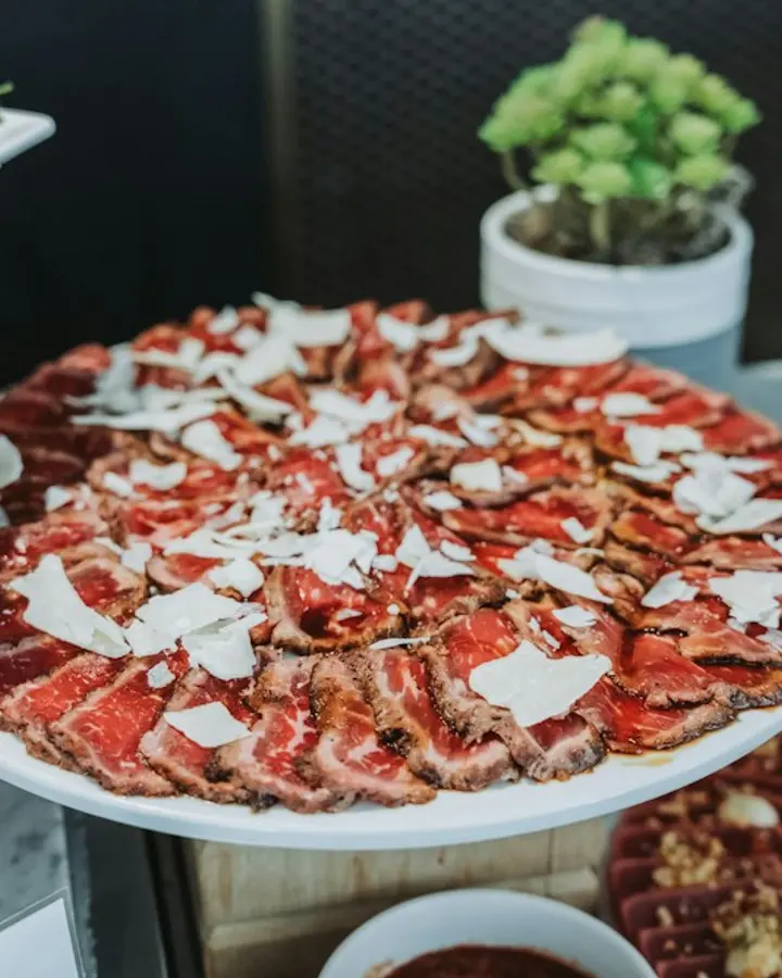 Carpaccio de wagyu — Alcaparras, rúcula e lascas de parmesão.